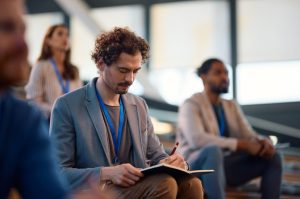 businessman-writing-in-notebook-while-participating-in-education-event-at-convention-center-.jpg